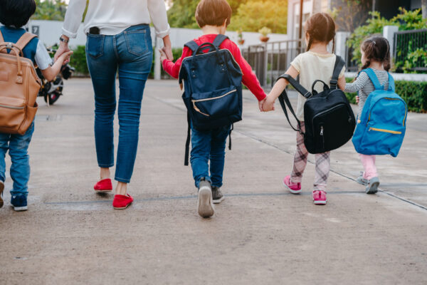 A mother leads her children to school on their first day back from holidays.